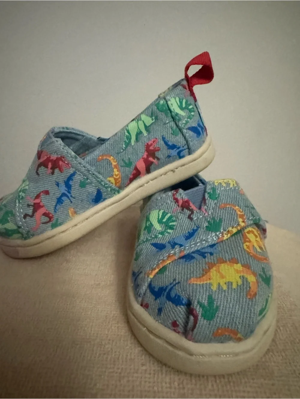 TOMS Kids Canvas Slip-Ons with Multicolor Dinosaur Print and Red Heel Tabs